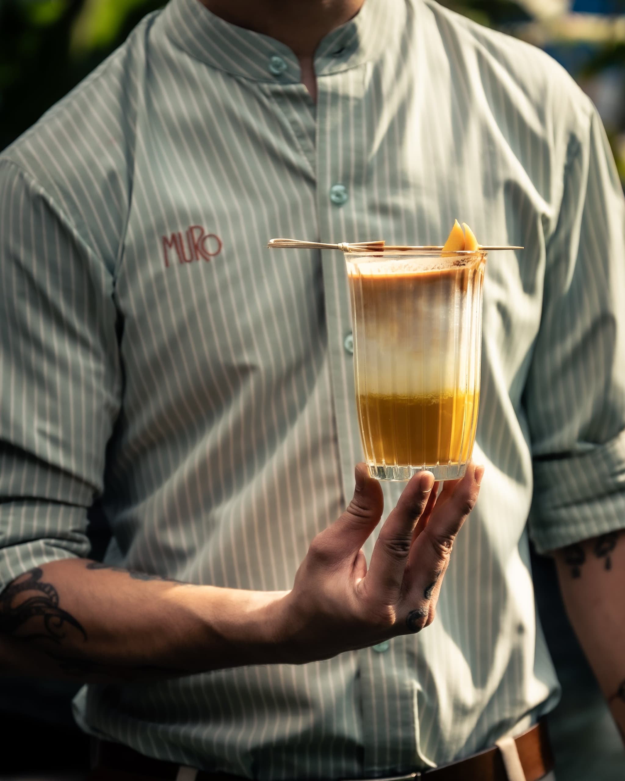 A layered MURO cocktail with a fruit garnish